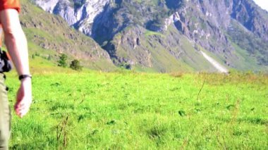 Sırt çantası ile yeşil dağ çayır üzerinde yürüyen adam hiking. Yaz spor ve eğlence kavramı.