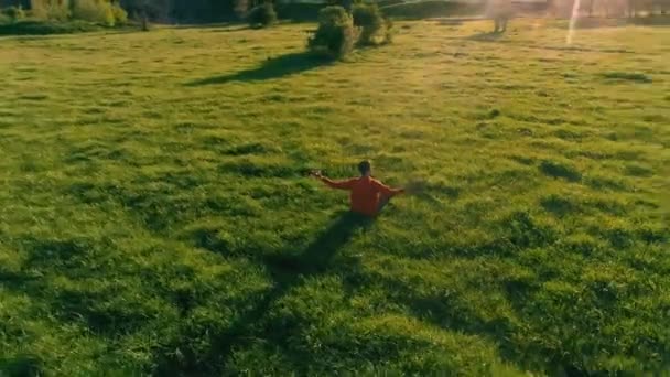 Vôo radial de baixa altitude sobre homem de ioga esporte na grama verde perfeita. Pôr do sol na montanha. — Vídeo de Stock