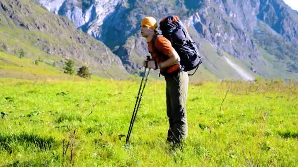 Sırt çantası ile yeşil dağ çayır üzerinde yürüyen adam hiking. Yaz spor ve eğlence kavramı. — Stok video