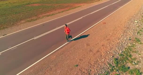 Voo de baixa altitude na frente do homem desportivo na estrada de asfalto perfeito — Vídeo de Stock
