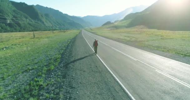Vol au-dessus de l'auto-stoppeur touristique marchant sur la route asphaltée. Grande vallée rurale au jour d'été. Sac à dos randonneur gars. — Video