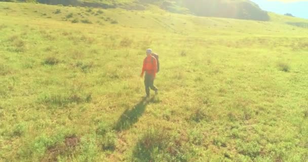 Flight over Backpack hiking tourist walking across green mountain field. Huge rural valley at summer day. — Stock Video