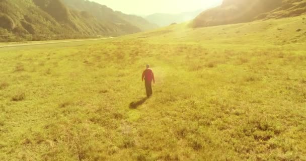 Πτήση πάνω από σακίδιο πεζοπορία τουρίστας με τα πόδια σε πράσινο πεδίο βουνό. Τεράστια αγροτική κοιλάδα την ημέρα του καλοκαιριού. — Αρχείο Βίντεο