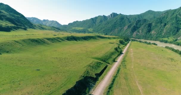 Route de montagne rurale aérienne et prairie au matin ensoleillé d'été. Asphalte autoroute et rivière. — Video