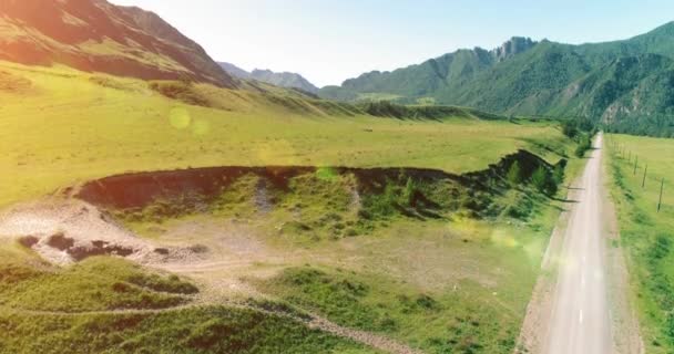 Aerial rural mountain road and meadow at sunny summer morning. Asphalt highway and river. — Stock Video