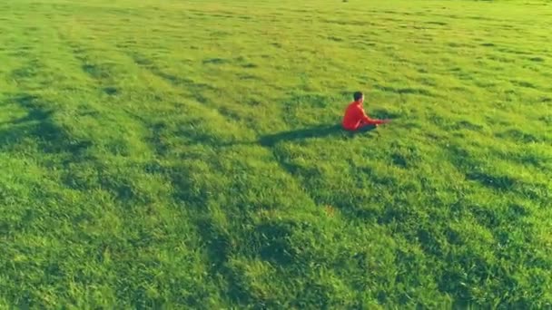 Lav højde radial flyvning over sport yoga mand i perfekt grønt græs. Solnedgang i bjerget. – Stock-video