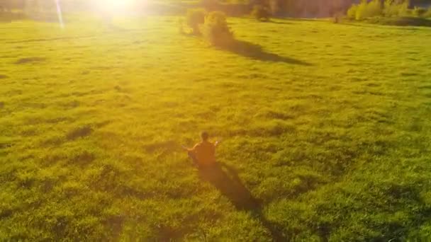 Volo radiale a bassa quota sopra lo sport yoga uomo a perfetta erba verde. Tramonto in montagna. — Video Stock