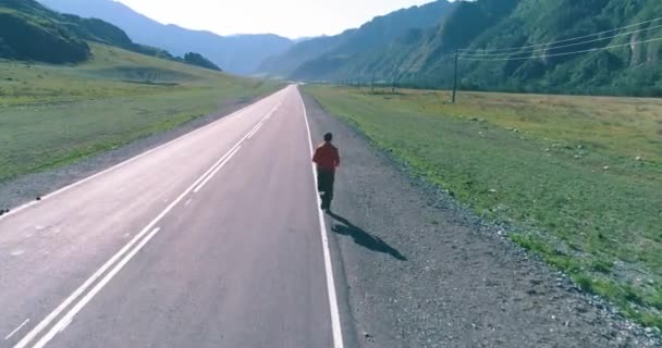 Lage hoogte vlucht voor sportieve man op perfecte asfaltweg — Stockvideo