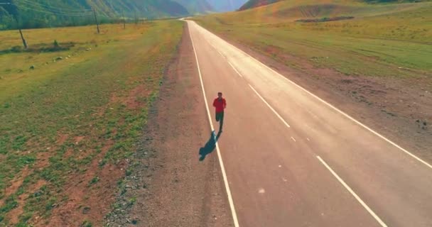 Lav højde flyvning foran sporty mand på perfekt asfalt vej – Stock-video
