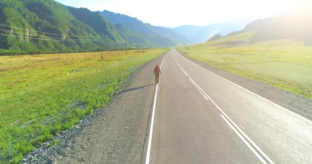 히치 하이킹을 하는 관광객 이 아스팔트 길을 걷는 모습. 여름철에는 거대 한 시골 계곡이 펼쳐져 있다. 배낭 여행자. — 비디오