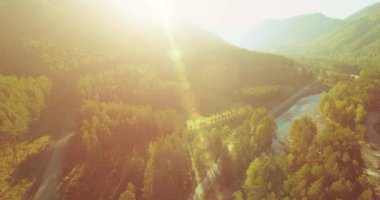 Güneşli yaz sabahında taze dağ nehri ve çayır üzerinde uçuşun ortasında. Aşağıdaki kırsal toprak yol.