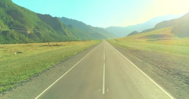 山岳道路上の航空低空の飛行と夏の朝の牧草地. — ストック動画