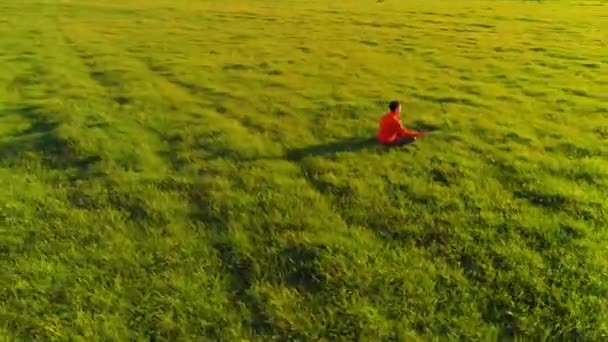 Vuelo radial de baja altitud sobre el hombre del yoga del deporte en hierba verde perfecta. Puesta de sol en montaña. — Vídeos de Stock