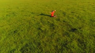 Yeşil çimlerde spor yogacısı üzerinde alçak irtifa radyal uçuş. Dağda gün batımı.