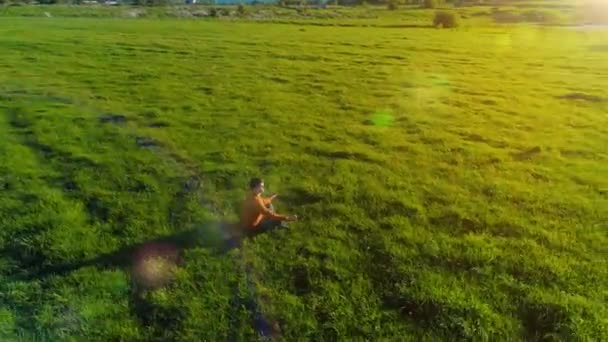 Lage hoogte radiale vlucht over sport yoga man op perfect groen gras. Zonsondergang in de bergen. — Stockvideo