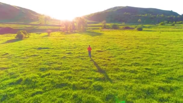 Volo sopra l'uomo di sport al prato verde perfetto dell'erba. Tramonto in montagna — Video Stock