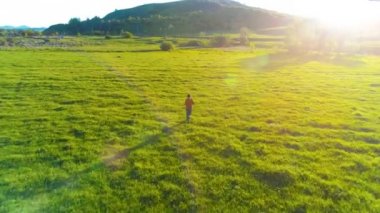 Mükemmel yeşil çayır üzerinde uçan bir sporcu. Dağda gün batımı