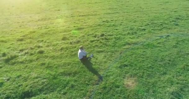 Vôo orbital baixo em torno do homem na grama verde com bloco de caderno no campo rural amarelo. — Vídeo de Stock