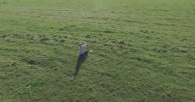 Yeşil çimlerin üzerinde sarı kırsal alanda not defteri olan bir adamın etrafında alçak yörünge uçuşları..
