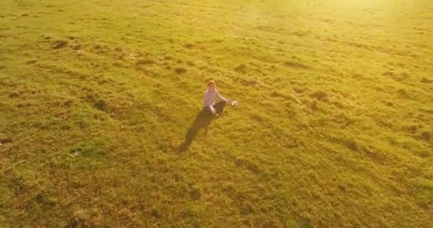 Vuelo orbital bajo alrededor del hombre sobre hierba verde con bloc de notas en el campo rural amarillo. — Vídeo de stock