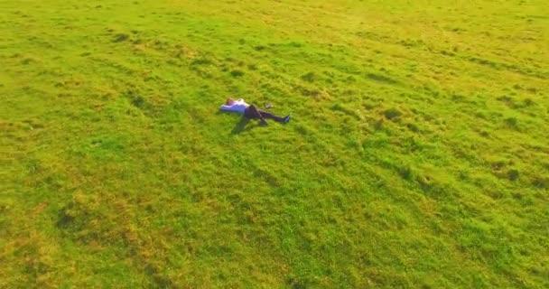 Niedriger Orbitalflug um den Menschen auf grünem Gras mit Notizblock auf gelbem Feld. — Stockvideo