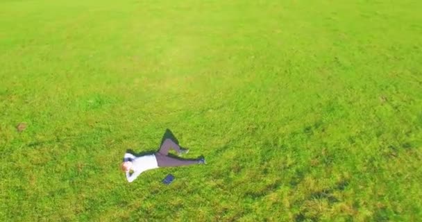 Low orbital flight around man on green grass with notebook pad at yellow rural field. — Stock Video