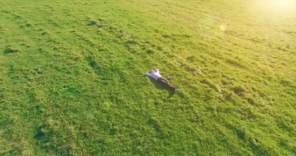 Nízká orbitální let kolem člověka na zelené trávě s poznámkovým blokem na žlutém venkovském poli. — Stock video
