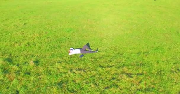 Low orbital flight around man on green grass with notebook pad at yellow rural field. — Stock Video