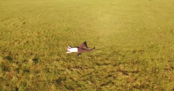 Lage baanvlucht rond mens op groen gras met notitieblok op geel landelijk veld. — Stockvideo