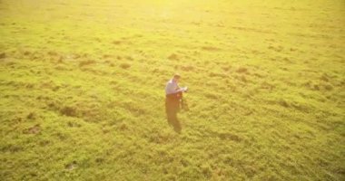 UHD 4k havadan görünümü. Defter pad ile yeşil çim sahasında oturan işadamı üzerinde düşük yörünge uçuş