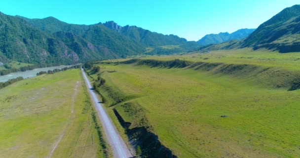 Luchtfoto landelijke bergweg en weide op zonnige zomerochtend. Asfaltweg en rivier. — Stockvideo