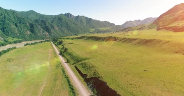 Route de montagne rurale aérienne et prairie au matin ensoleillé d'été. Asphalte autoroute et rivière. — Video