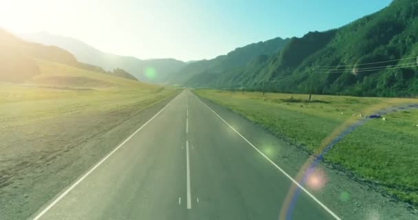 Tiefflug über Bergstraße und Wiese bei sonnigem Sommermorgen. — Stockvideo