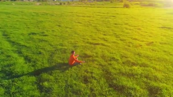 Vuelo radial de baja altitud sobre el hombre del yoga del deporte en hierba verde perfecta. Puesta de sol en montaña. — Vídeos de Stock