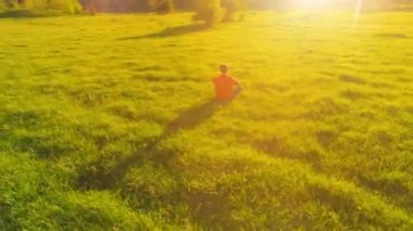 Yeşil çimlerde spor yogacısı üzerinde alçak irtifa radyal uçuş. Dağda gün batımı.