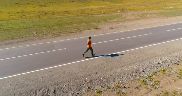 Voo de baixa altitude na frente do homem desportivo na estrada de asfalto perfeito — Vídeo de Stock