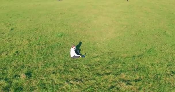 Alacsony orbitális repülés körül férfi zöld füvön notebook pad sárga vidéki területen. — Stock videók