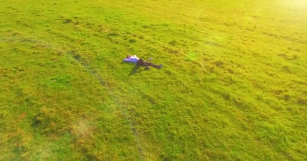 Niedriger Orbitalflug um den Menschen auf grünem Gras mit Notizblock auf gelbem Feld. — Stockvideo