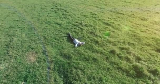 Lage baanvlucht rond mens op groen gras met notitieblok op geel landelijk veld. — Stockvideo