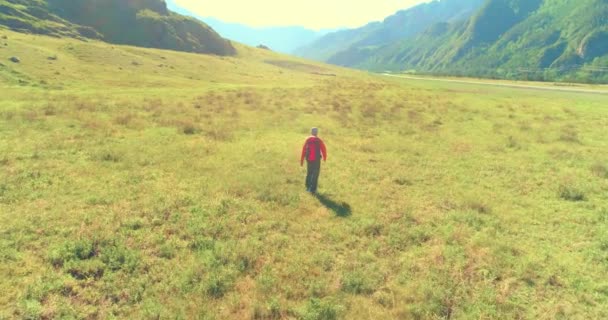 Volo sopra Zaino escursionistico turistico passeggiando attraverso il campo di montagna verde. Enorme valle rurale al giorno d'estate. — Video Stock