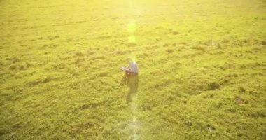 UHD 4k havadan görünümü. Defter pad ile yeşil çim sahasında oturan işadamı üzerinde düşük yörünge uçuş