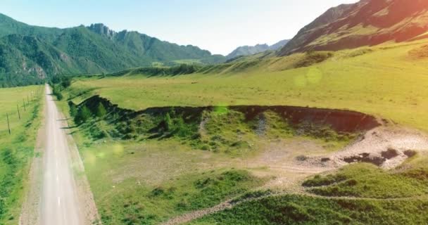 Légi vidéki hegyi út és rét napos nyári reggelen. Aszfalt autópálya és folyó. — Stock videók