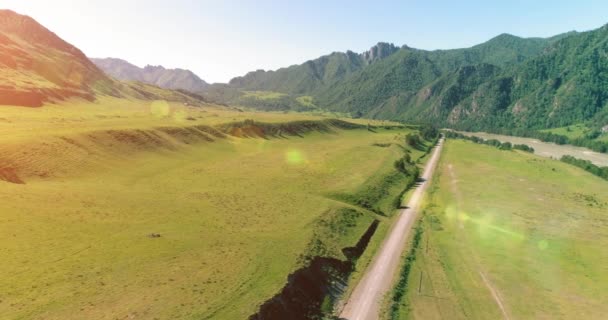 Route de montagne rurale aérienne et prairie au matin ensoleillé d'été. Asphalte autoroute et rivière. — Video