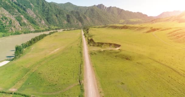 Luftlinie ländliche Bergstraße und Wiese an einem sonnigen Sommermorgen. Asphaltstraße und Fluss. — Stockvideo