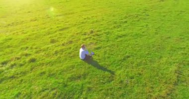 Yeşil çimlerin üzerinde sarı kırsal alanda not defteri olan bir adamın etrafında alçak yörünge uçuşları..