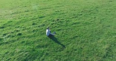 Yeşil çimlerin üzerinde sarı kırsal alanda not defteri olan bir adamın etrafında alçak yörünge uçuşları..