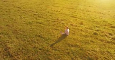 Yeşil çimlerin üzerinde sarı kırsal alanda not defteri olan bir adamın etrafında alçak yörünge uçuşları..