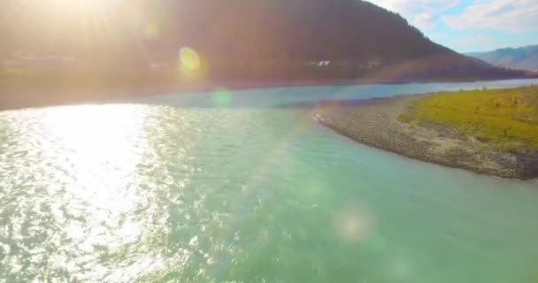 Vol à basse altitude au-dessus d'une rivière de montagne fraîche et rapide avec des rochers au soleil matin d'été. — Video