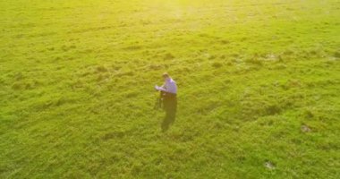 UHD 4k havadan görünümü. Defter pad ile yeşil çim sahasında oturan işadamı üzerinde düşük yörünge uçuş