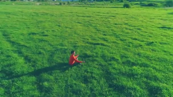 Vuelo radial de baja altitud sobre el hombre del yoga del deporte en hierba verde perfecta. Puesta de sol en montaña. — Vídeo de stock